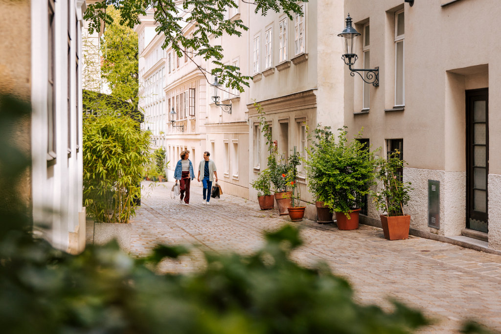 Romantische Strasse mit Kopfsteinpflaster, viel Grün und zwei Passant*innen